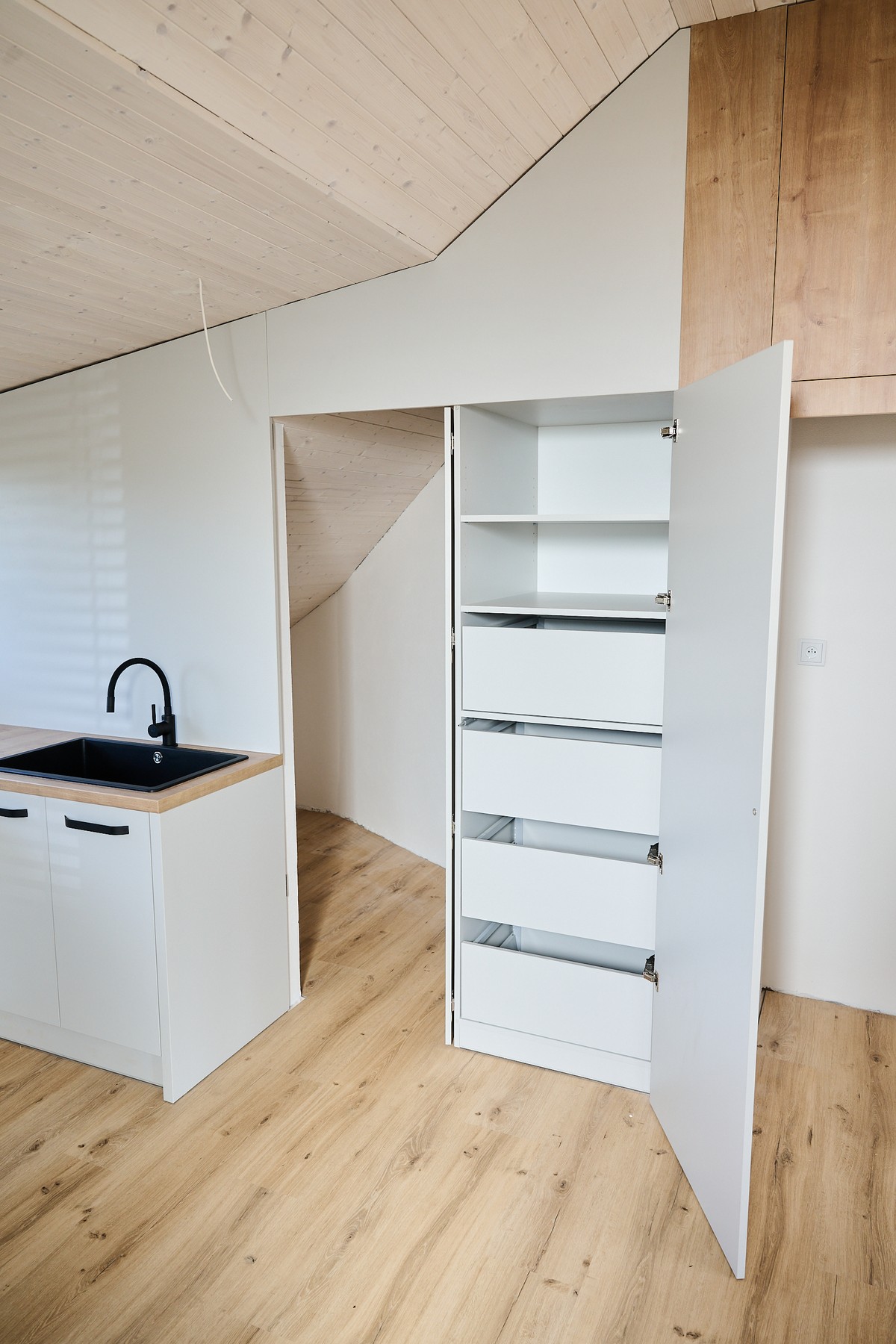 Bílá kuchyň v podkroví - vertikální pohled na úložné systémy